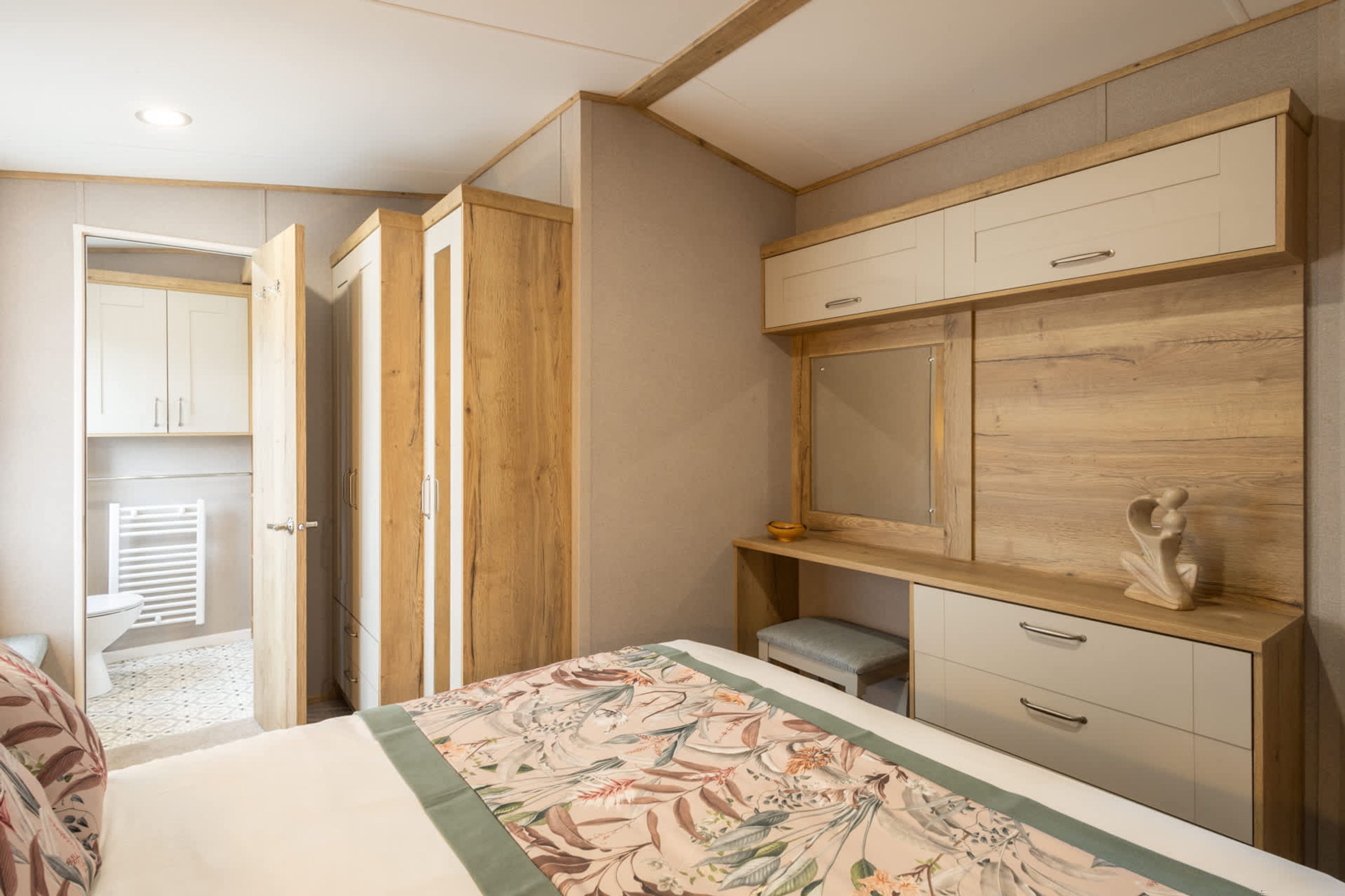 A bedroom with a bed, wooden wardrobe, and a small desk.
