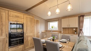 Eine moderne Küche mit Holzschränken, einem eingebauten Backofen und einem Essbereich mit Tisch für vier Personen.