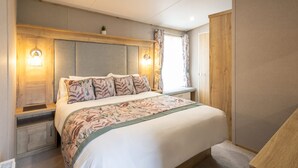 Ein Schlafzimmer mit Bett, Nachttischen, Kopfteil und Wandleuchten.