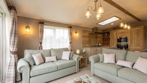 Ein geräumiges Wohnzimmer mit zwei Sofas, einem Couchtisch und einer Küchenzeile mit Holzschränken und modernen Geräten.