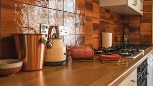 A kitchen with a copper pot, a white kettle, a red towel, and a stove. - Host Stay The Bothy (Lyme Regis)