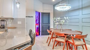 A modern kitchen with a marble countertop, a built-in blender, and a dining area with a wooden table and chairs.