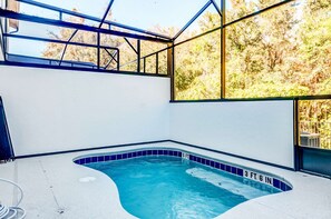 An indoor swimming pool with clear blue water, surrounded by white walls and a glass enclosure.