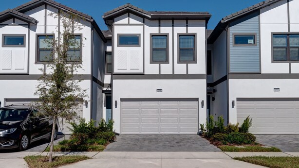 A row of modern townhouses with white exteriors, grey trim, and a central garage.