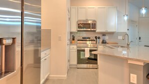 A modern kitchen with stainless steel appliances, white cabinetry, and a granite countertop.