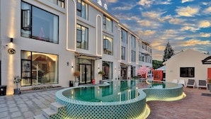 A modern hotel with a large outdoor swimming pool, a well-lit entrance, and a clear view of the sky. - Xiangyun Qinzi hotel (Shanghai)
