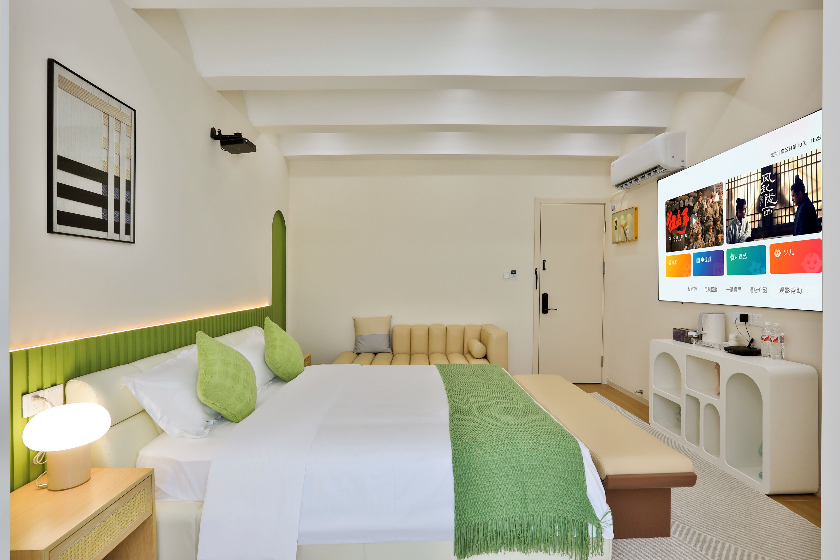 A modern hotel room with a large bed, bedside tables, a TV, and a green accent wall.
