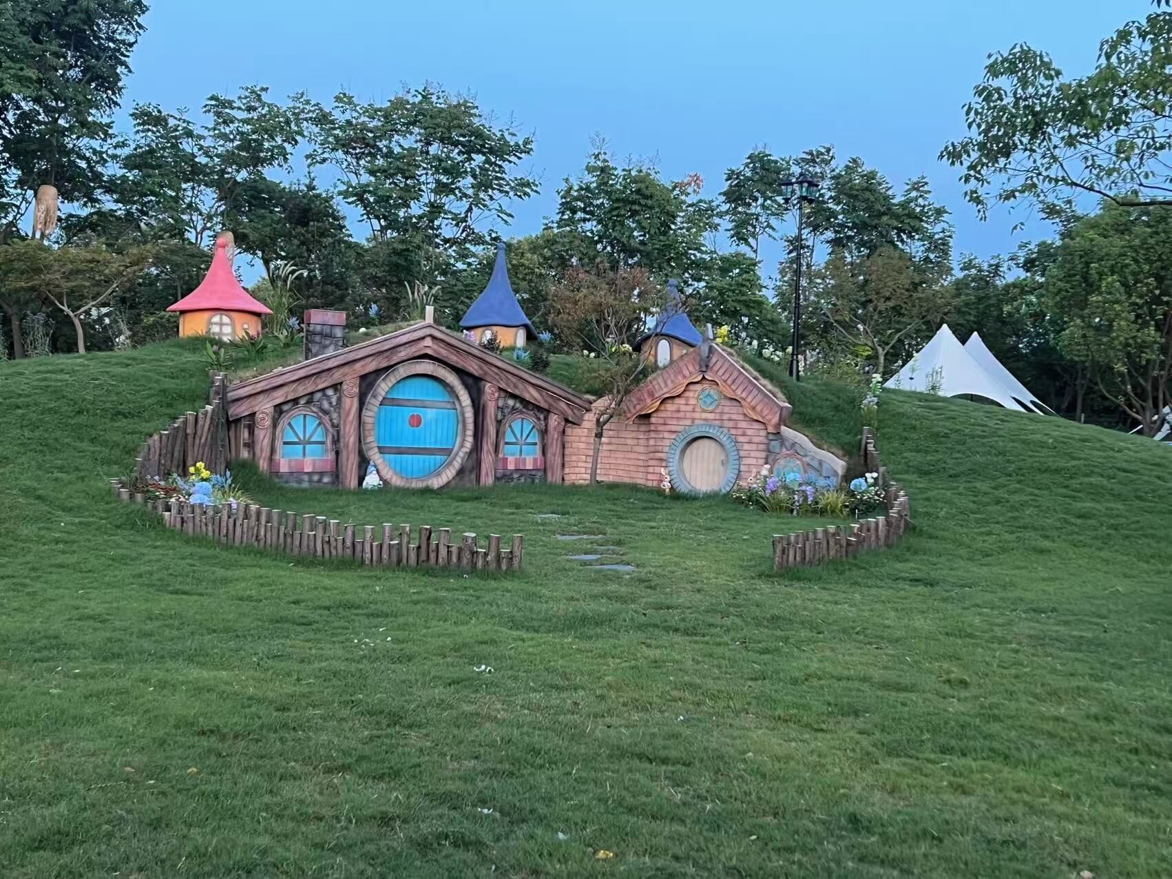 A grassy area with Hobbit-style houses and a white tent.