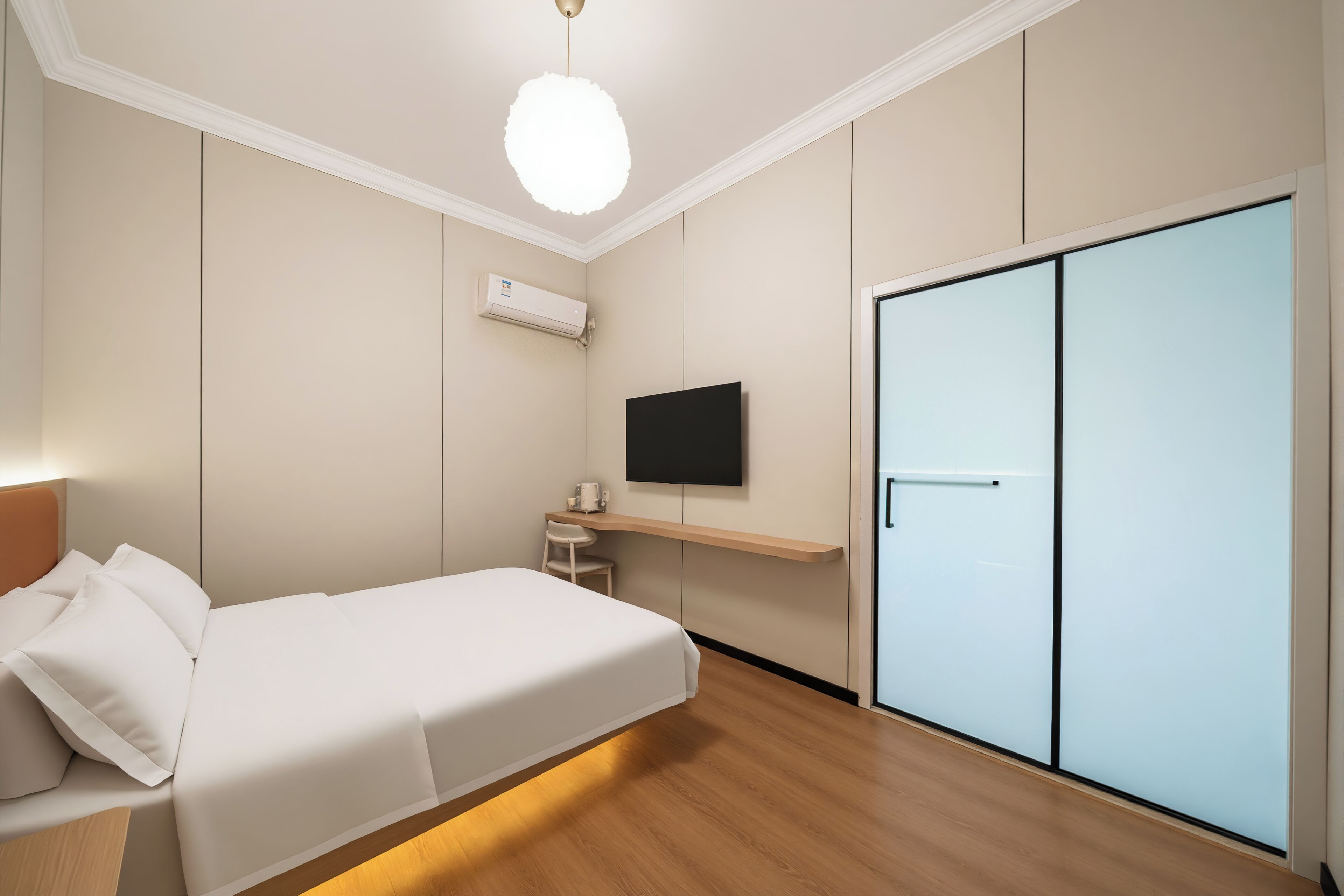 A modern bedroom with a bed, a TV, a wardrobe, and a desk with a chair.