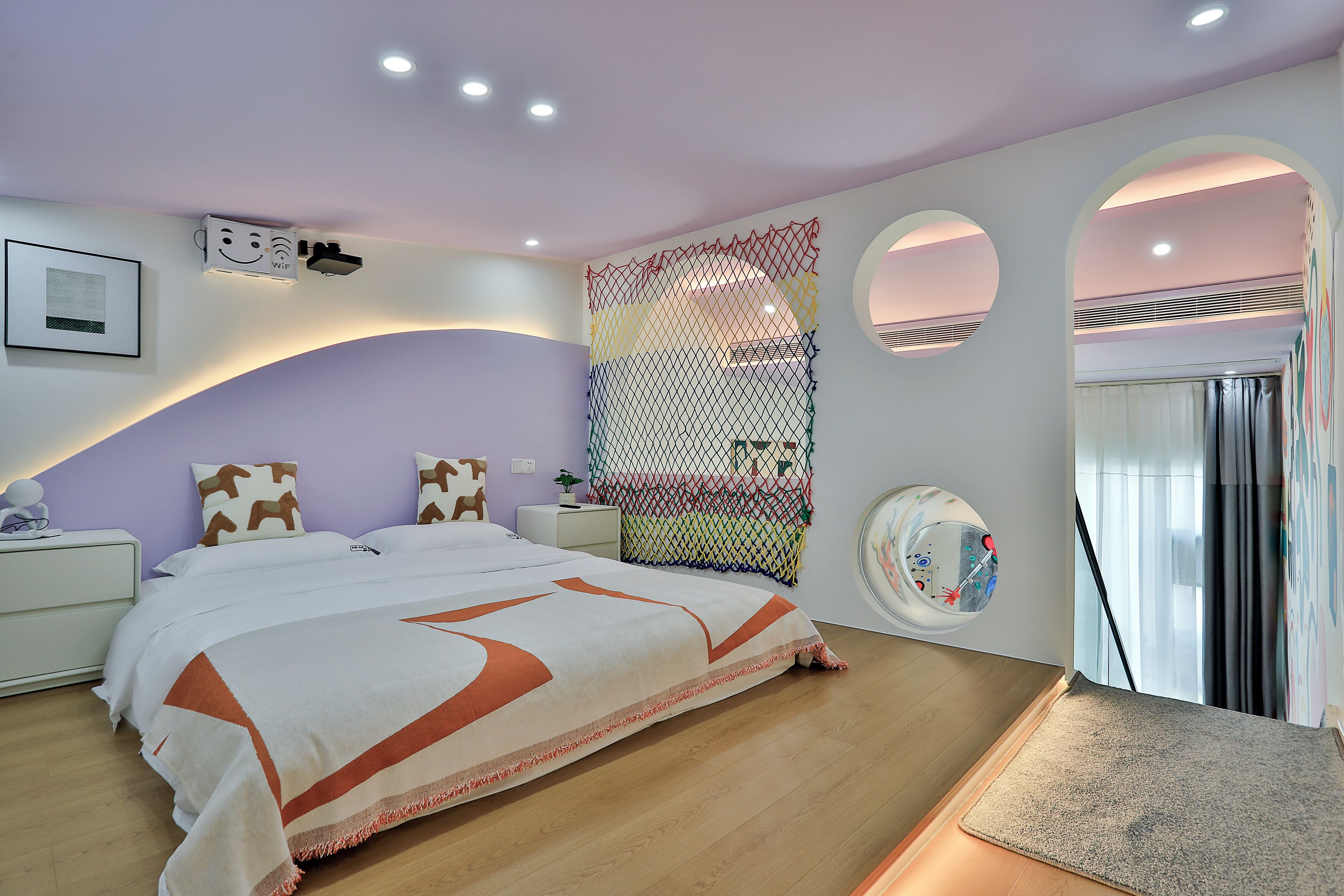 A modern bedroom with a bed, nightstands, a decorative wall, and a circular window.