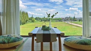 A view from a room with a wooden table and cushions, a vase with flowers, and a clear sky. - Xiangyun Qinzi hotel (Shanghai)