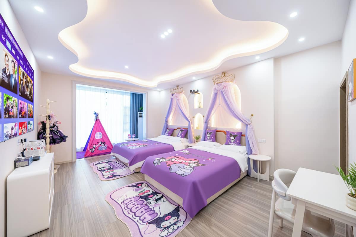 A modern bedroom with two beds, a desk, and a small table.