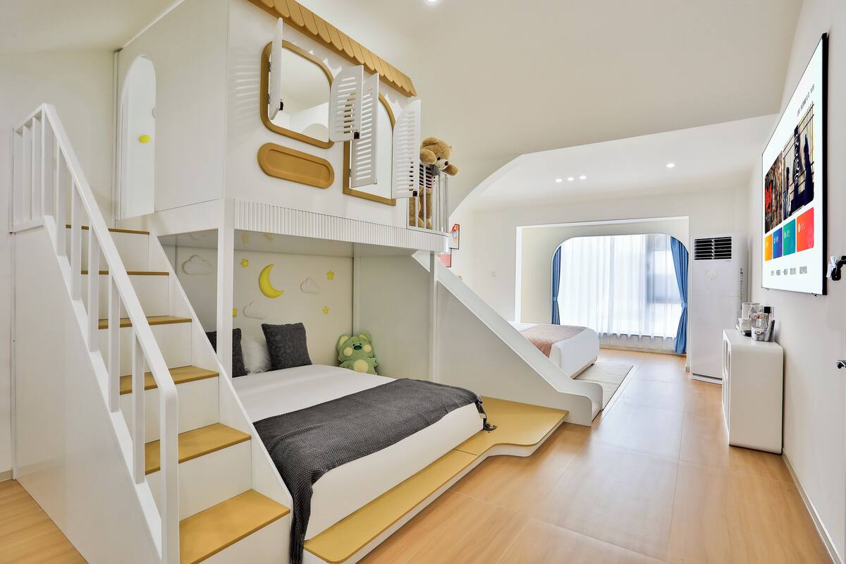 A modern bedroom with a bunk bed, a staircase, a small desk, and a large window.