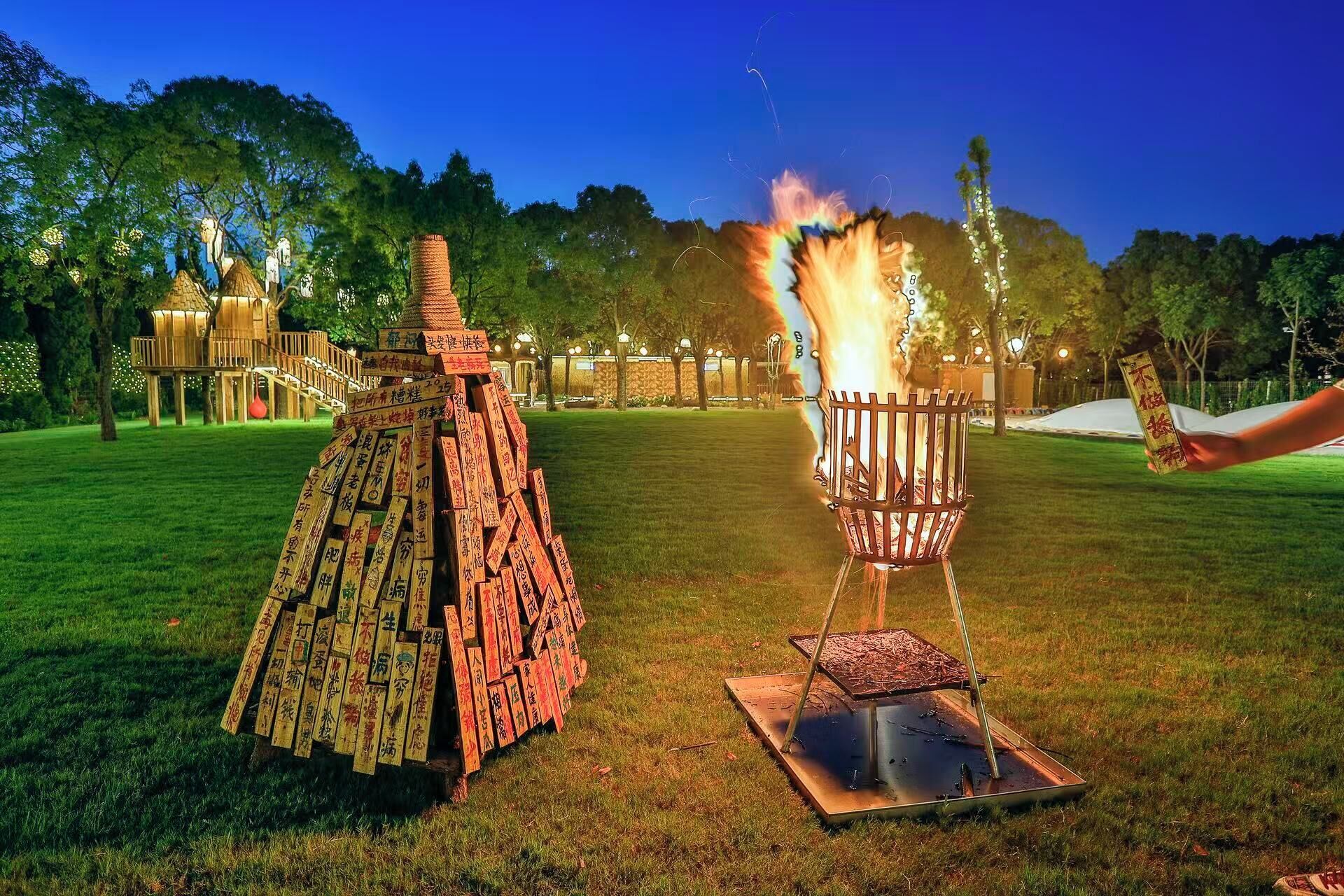 A wooden structure with multiple levels and a fire burning in a metal container.
