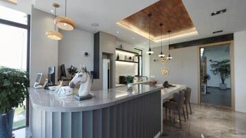 A modern reception area with a curved counter, pendant lighting, and a large window.