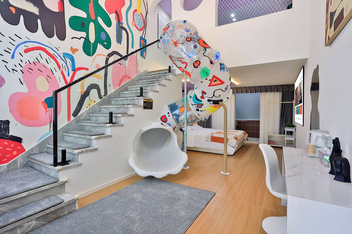 A modern interior with a white spiral staircase, a colorful abstract mural, a white sofa, and a dining area with a white table and chairs.