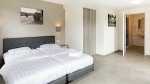 A bedroom with a large bed, a nightstand, and a wall-mounted lamp. - Summio Bungalowpark De Riethorst (Plasmolen)