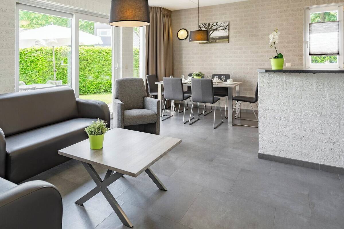 A modern living room with a sofa, a coffee table, and a dining area with chairs and a table.