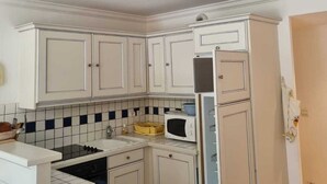 Una cocina compacta con alacenas blancas, un microondas y una estufa.