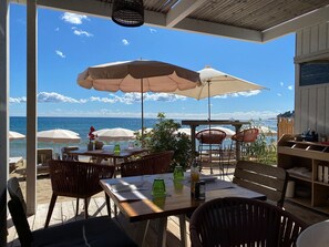 An outdoor seating area with tables and chairs, overlooking the sea. - Very nice apartment for 4 people, 2 bedrooms, beautiful living room and terrace. (Cavalaire-sur-Mer)