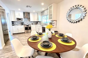 A modern kitchen with white cabinets, a stainless steel range hood, and a stone backsplash.