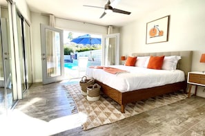 A bedroom with a bed, a ceiling fan, a framed picture, and a view of a swimming pool through the glass doors. - Fantastic MidCentury Modern, Pool, Views, Privacy! (Palm Springs)