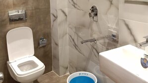 A modern bathroom with a toilet, shower, and sink. - Powai Inn (Mumbai)