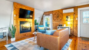 Ein gemütliches Wohnzimmer mit Kamin, einem blauen Sofa und einer Holzwand.