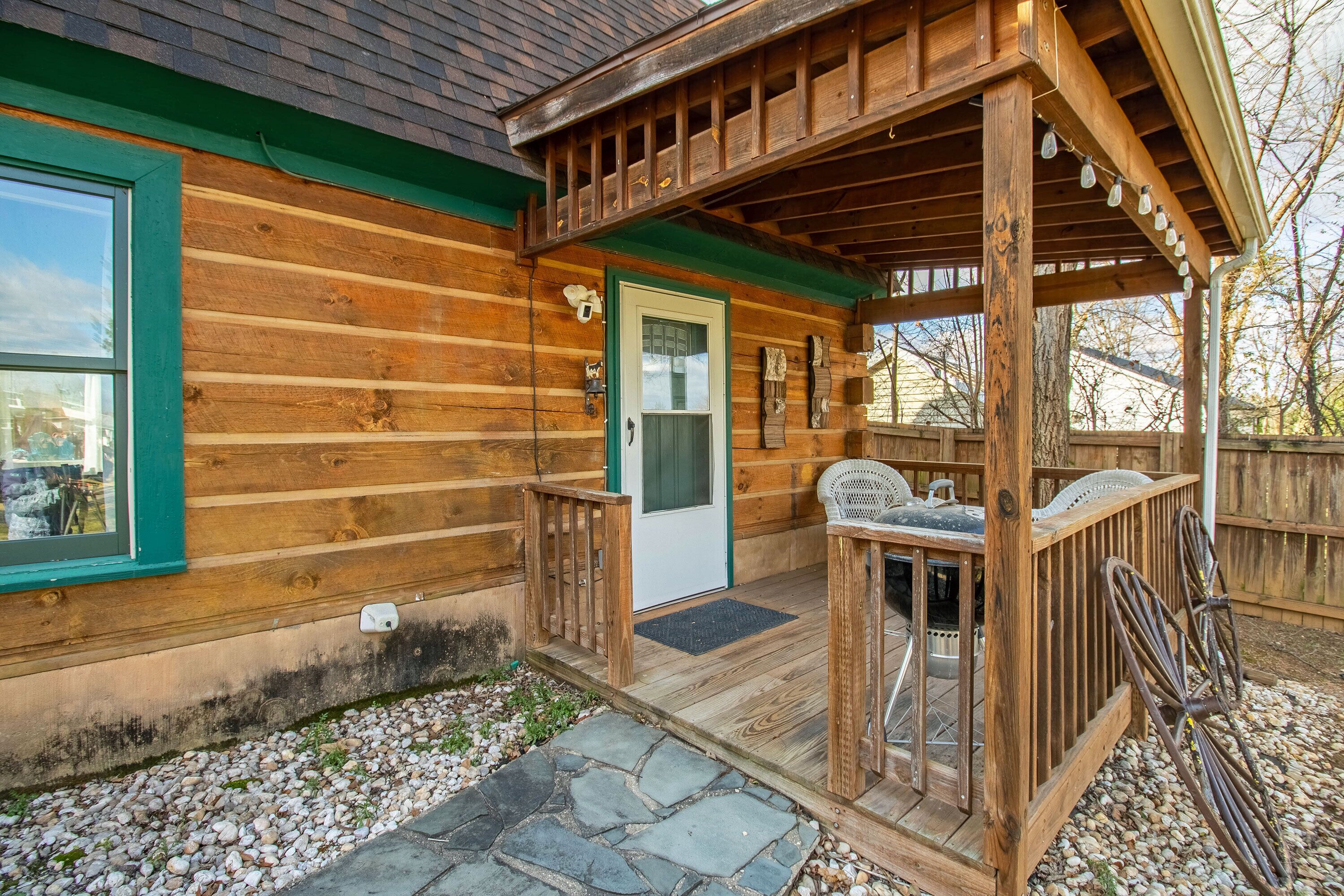 A wooden cabin with a porch, a door, and a small outdoor seating area.