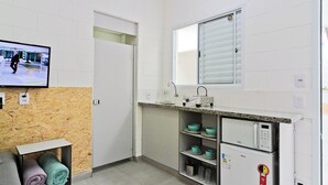 Eine kleine Küchenzeile mit einer Mikrowelle, einem Spülbecken und einem Fenster mit Jalousien.