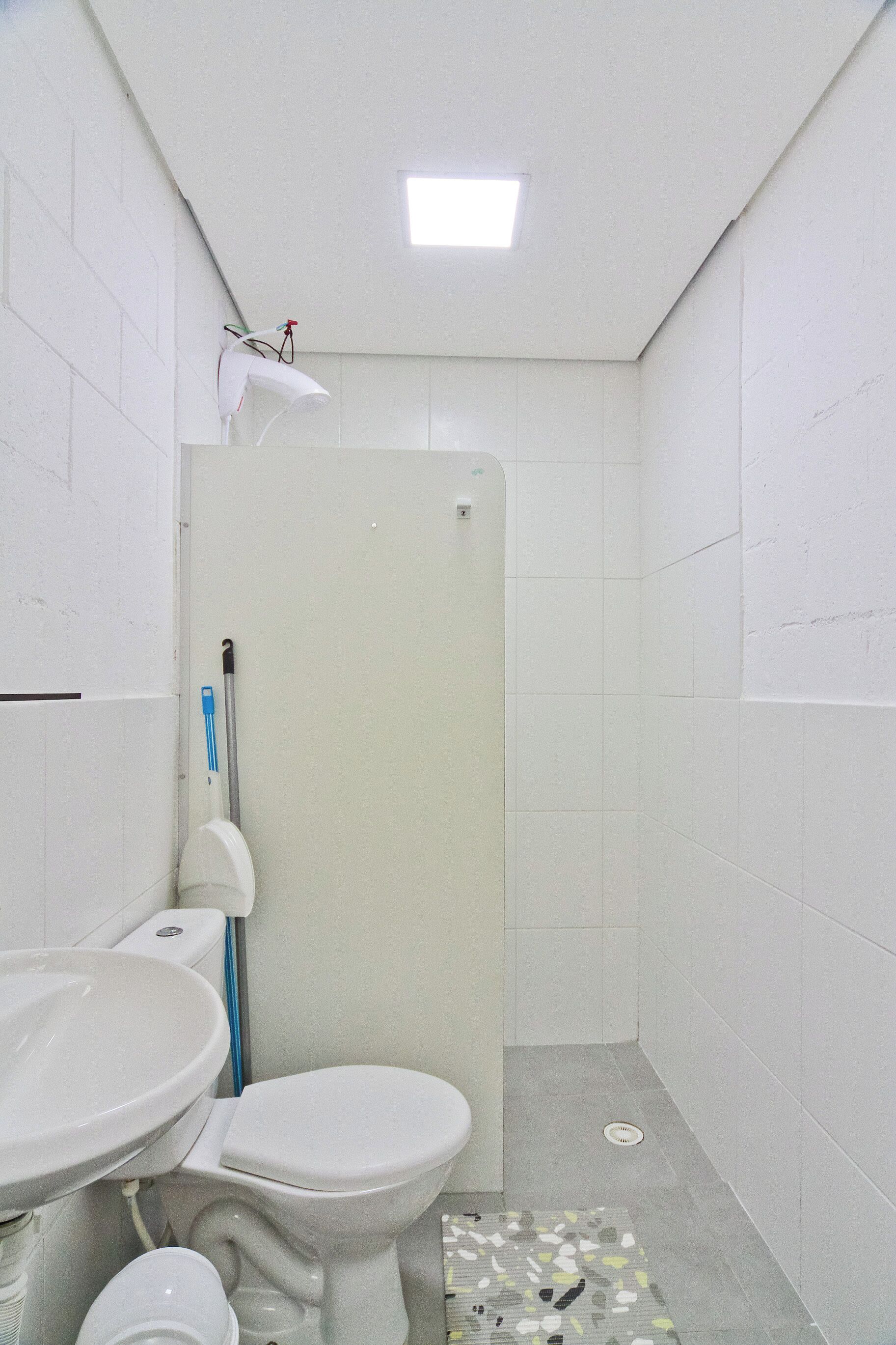 A small, clean bathroom with a toilet, sink, and shower.