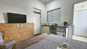 Ein Hotelzimmer mit Bett, Fernseher, Küchenzeile und einer Schiebetür.