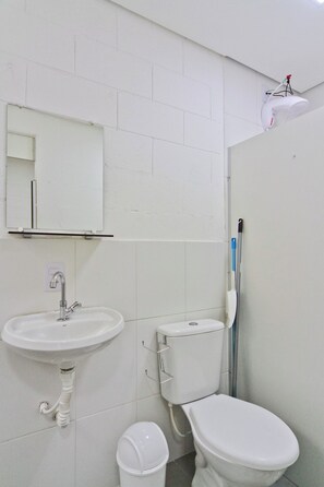 A small, clean bathroom with a white sink, toilet, and a mirror above the sink. - Vila 50 (Sao Paulo)
