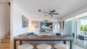 A modern kitchen with a bar area, a ceiling fan, and a large window overlooking a balcony.