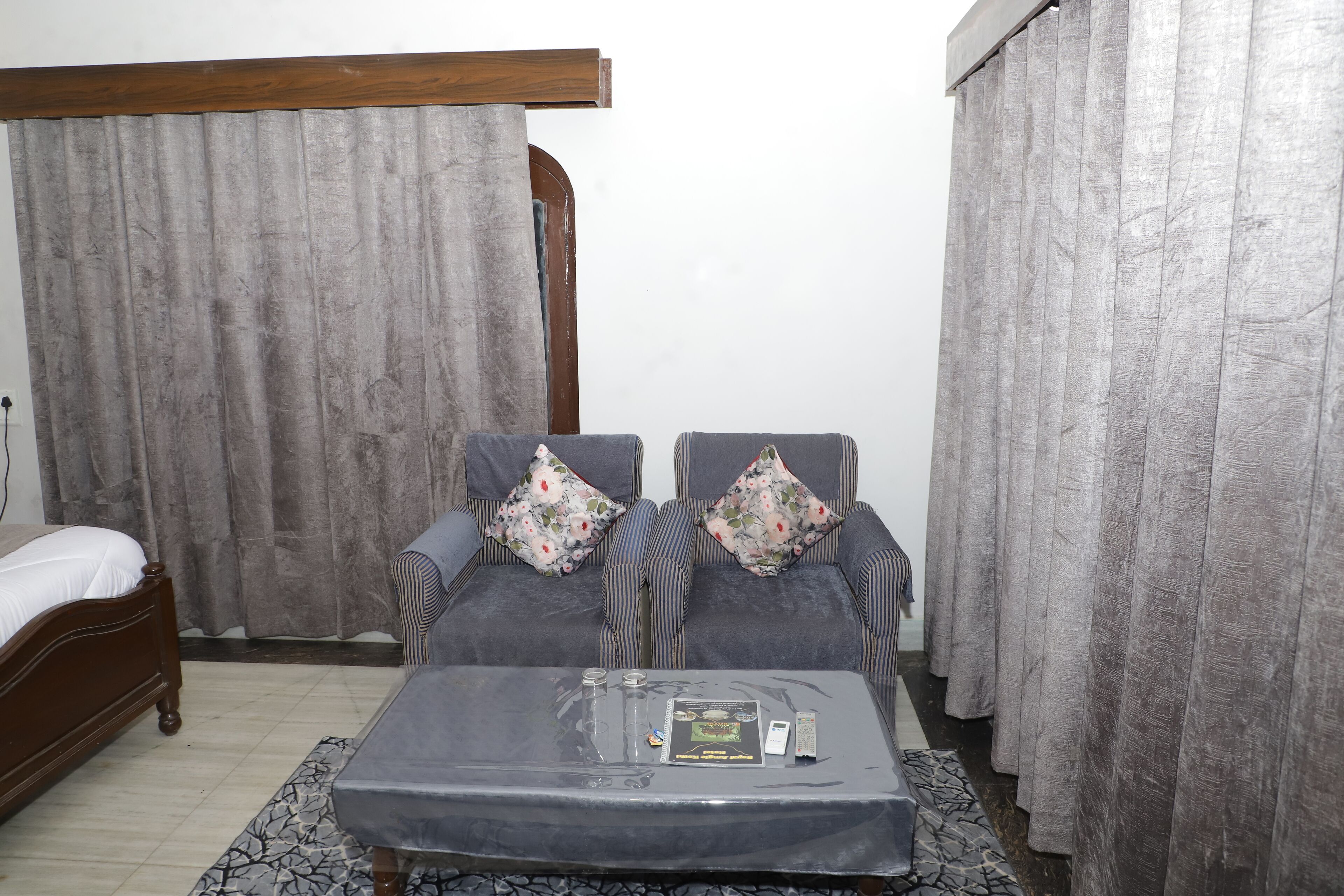 A bedroom with a bed, a sofa, a coffee table, and curtains.