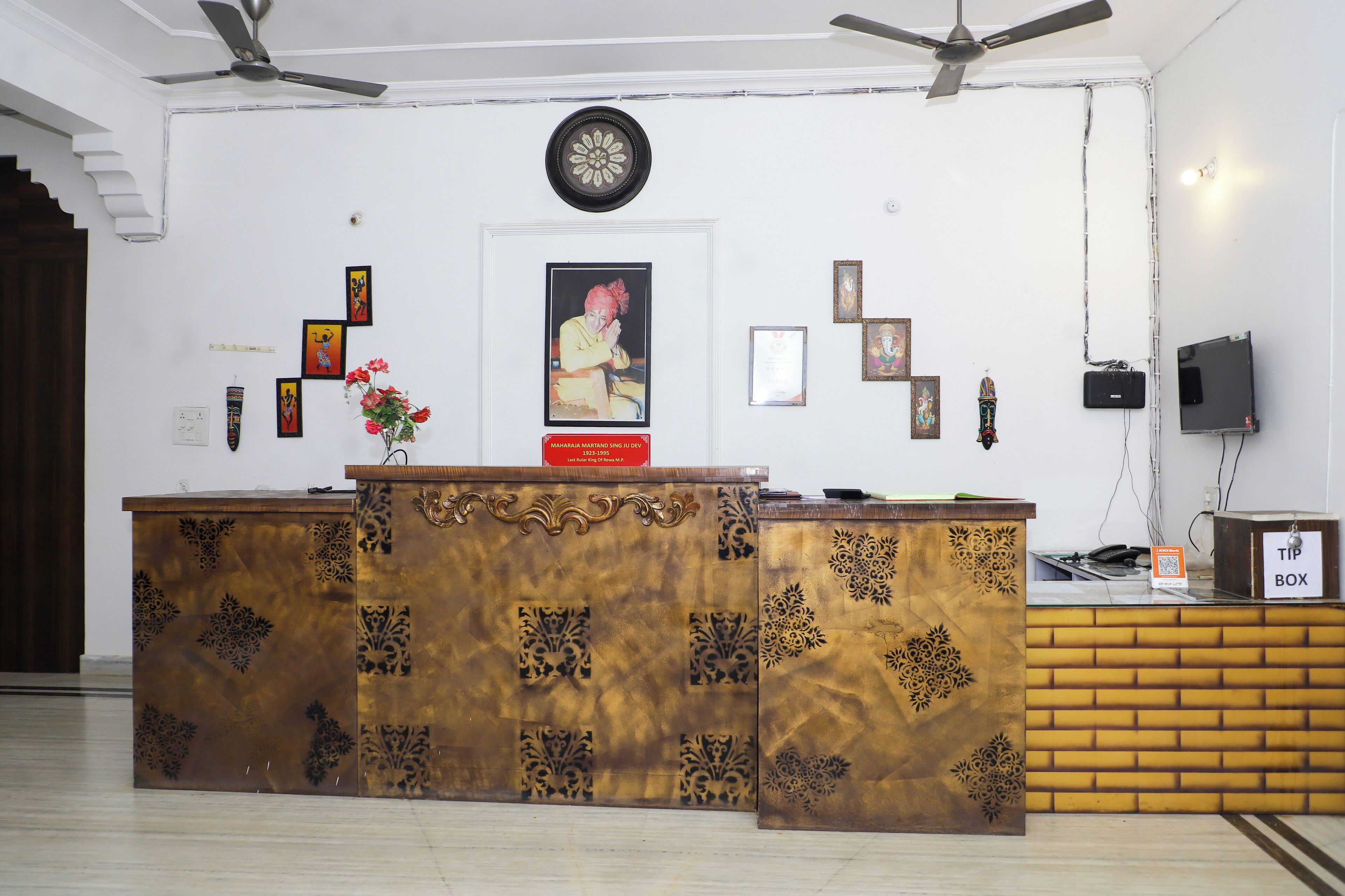 A reception desk with a clock above it, framed pictures on the wall, and a television on the right.