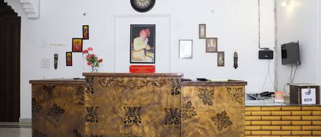 A reception desk with a clock above it, framed pictures on the wall, and a television on the right.