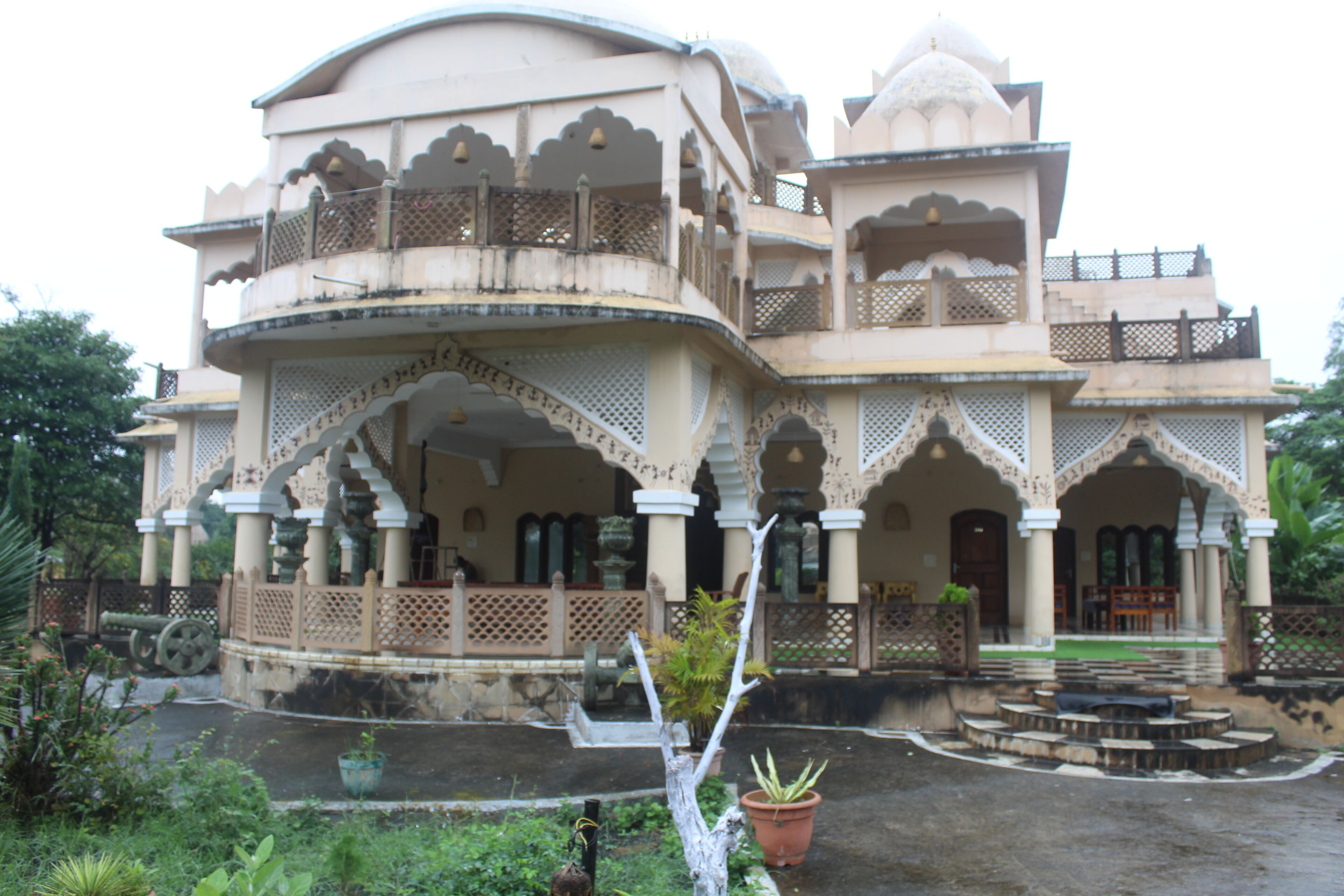 A traditional building with multiple balconies and arches, featuring a courtyard with steps and potted plants.