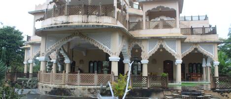 A traditional building with multiple balconies and arches, featuring a courtyard with steps and potted plants.