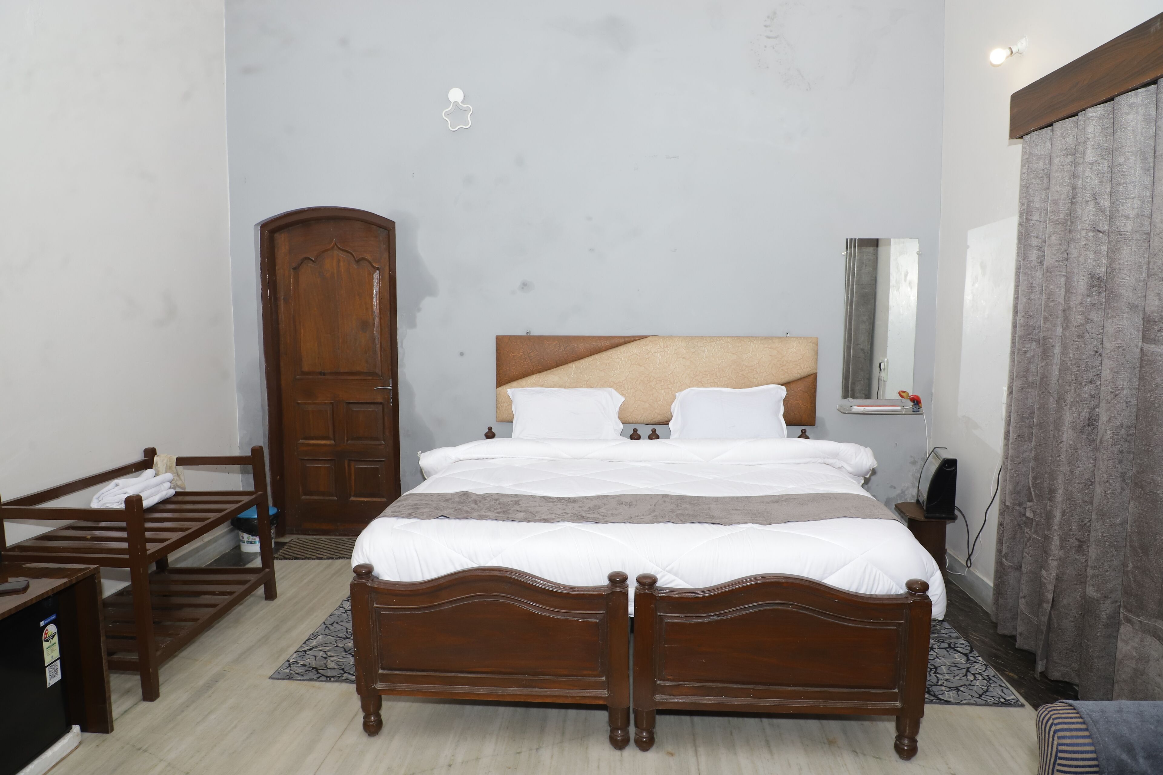 A bedroom with a wooden bed, a wardrobe, a desk, and a mirror.