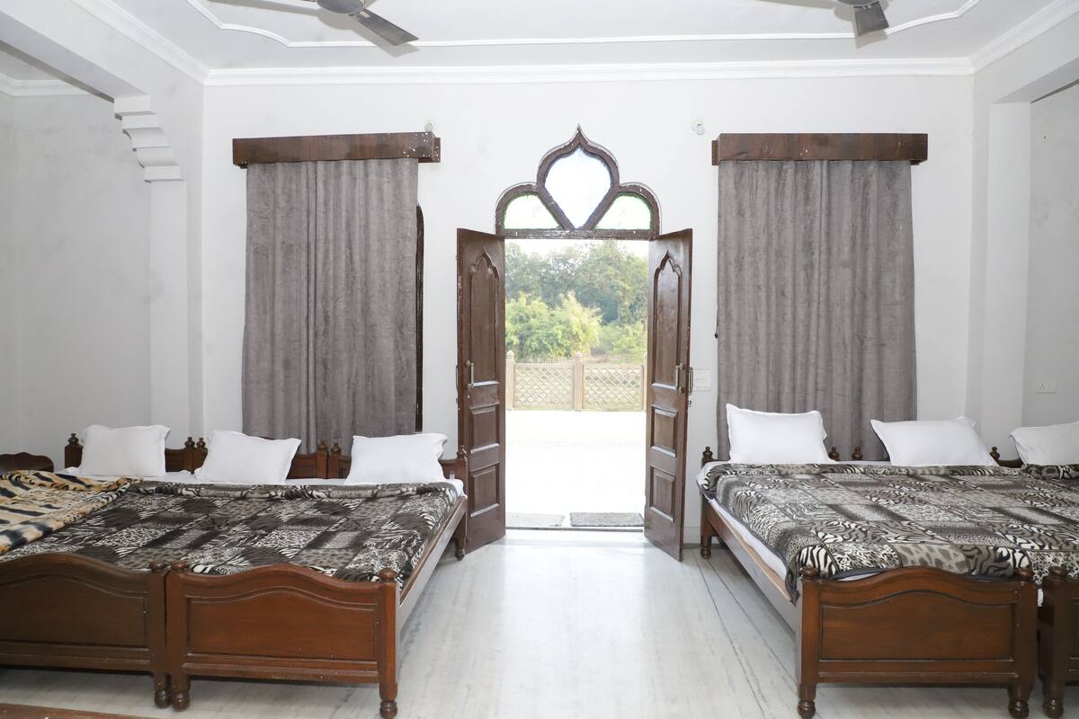 A bedroom with two wooden beds, a large window, and a view of greenery outside.