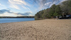 Une plage de sable avec un lac, des arbres et des véhicules de loisirs.