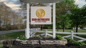 Une enseigne pour Sun Retreats Peters Pond, avec une clôture blanche et de la verdure en arrière-plan.