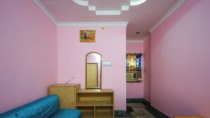 A pink-walled room with a wooden bench, a small table, a mirror, and a shelf.