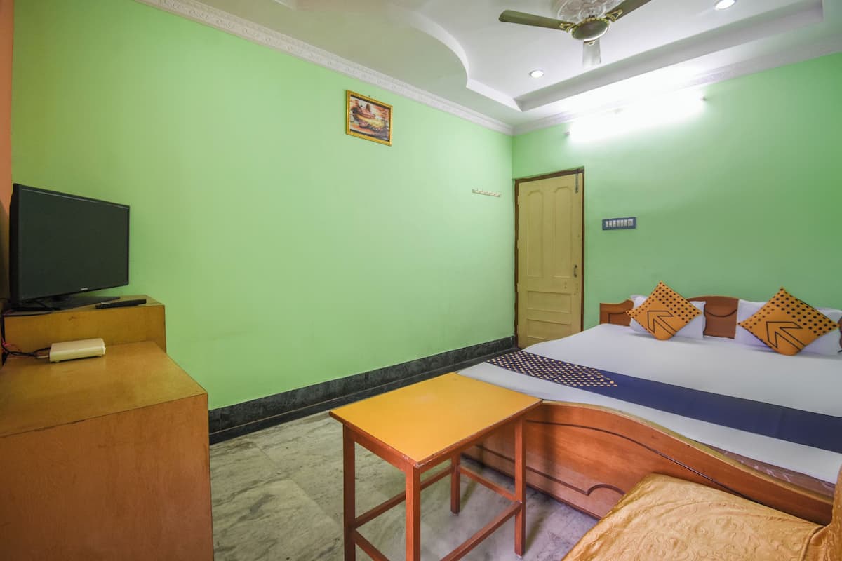 Quarto de hotel com cama, secretária, televisão e porta.