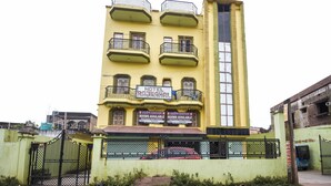 A multi-story building with balconies, a sign indicating 'Hotel Rajmahal' and 'Rooms Available'.