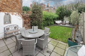 Une terrasse avec des meubles en osier, une table ronde et une plante en pot.