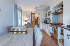 A kitchen with a wooden table, a built-in oven, and a staircase leading to a loft.