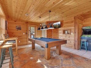 A wooden interior with a pool table, bar stools, and a billiards table. - Breathtaking Views | Close To Dollywood | Hot Tub | Pool Table | WiFi (Sevierville)