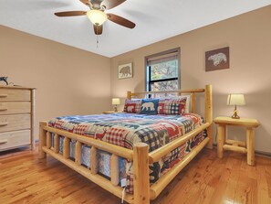 Ein Schlafzimmer mit einem hölzernen Bett, einem Deckenventilator, einem Fenster mit Jalousien und einer Kommode.